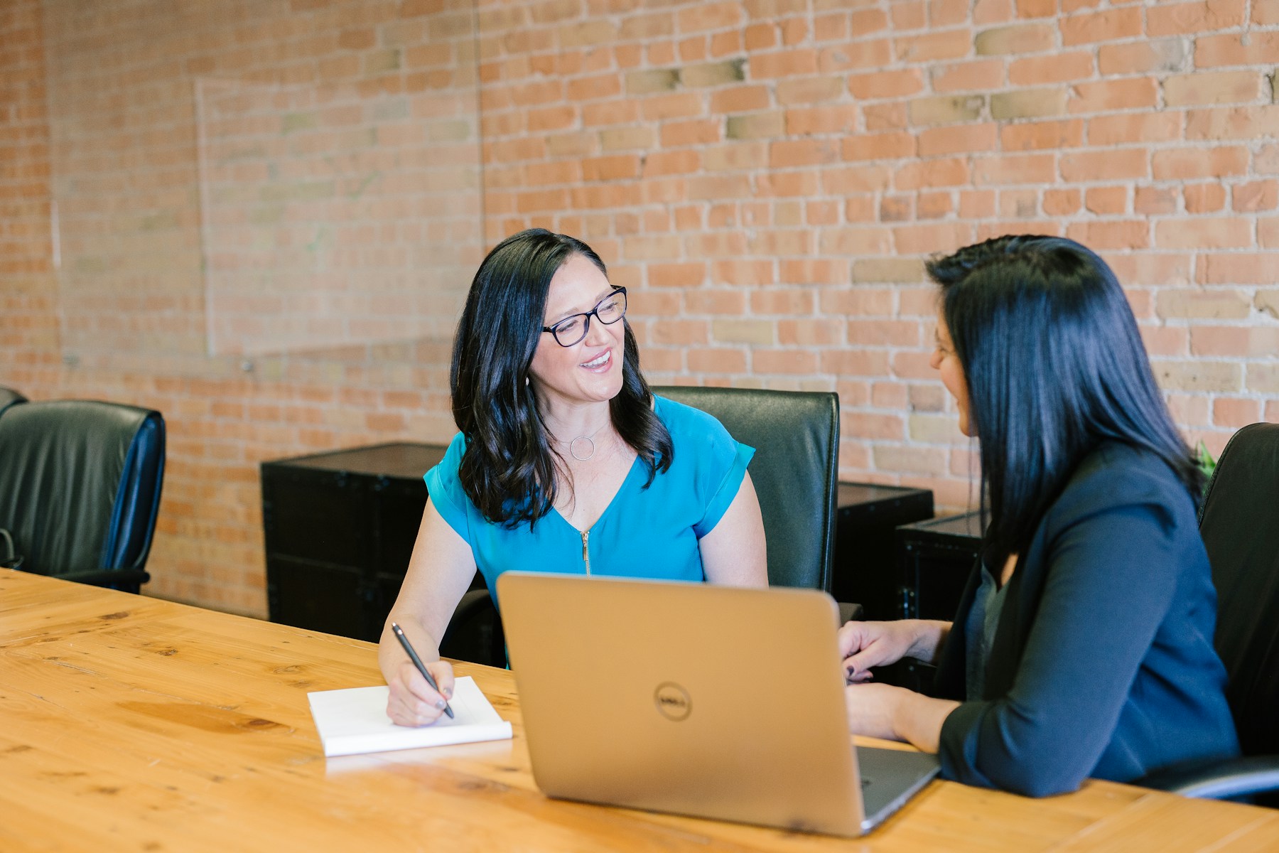 Two business professionals in a relaxed conversation at a wooden table